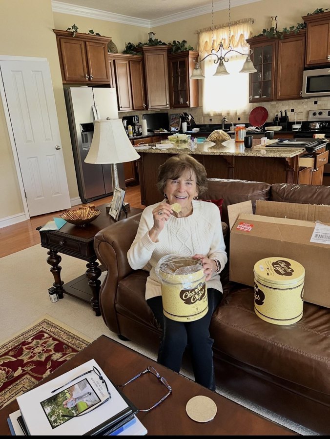 A mother holding her Charles Chips tin, a gift from her daughter